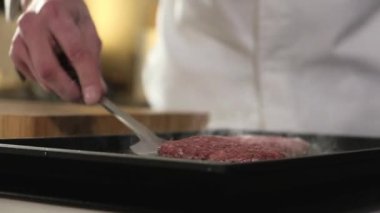 Et köftesi sıcak ızgarada pişirilir. Aşçı spatulada hamburgeri çevirir. Restoranda fast food. Hamburger kızartması için leziz et. Lezzetli ev yapımı hamburgerlerle barbekü.