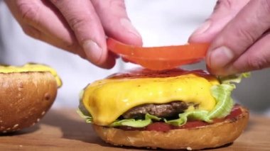 Lezzetli ev yapımı hamburger. Şef, restoranın mutfağına kızarmış çörek köfteli soğan peynirli domates sosu döker. Hamburger sokak yemeği yapıyorum. Yakın plan. Sağlıksız yaşam tarzı