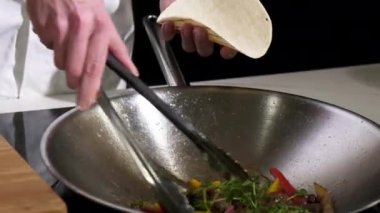 Mutfaktaki yetişkin profesyonel şef Meksika dürümlü tortilla dolduruyor. Sokak yemekleri ulusal Meksika yemeğidir. Lokantada doyurucu bir atıştırmalık. yakın plan