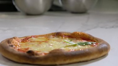 Ev yapımı pizza. Fırıncı servis etmeden önce fırından çıkan peynirle taze bir pizza süsler. İtalyan geleneksel yemeği.