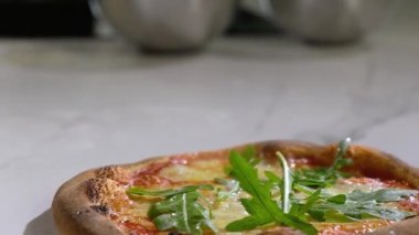 Ev yapımı pizza. Fırıncı servis etmeden önce fırından çıkan peynirle taze bir pizza süsler. İtalyan geleneksel yemeği.
