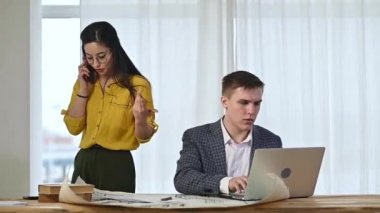 Çok uluslu ofis. Avrupalı genç erkek mimar masada oturur ve dizüstü bilgisayara veri yazar. Asyalı tasarımcı kız telefonda bir müşteriyle konuşuyor. Çalışma alanı çizimler ve tasarım projeleri içerir