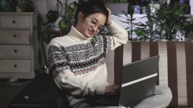 Akşamları sıcak süveter giyen serbest çalışan genç Asyalı kadın oturma odasındaki kanepede oturuyor ve dizüstü bilgisayarla çalışıyor. Kız evdeki bilgisayarda rahatça yazabiliyor. Merkez Karantina