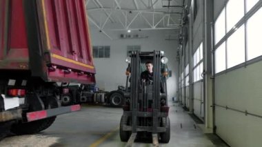 Santral tamircisi büyük bir tamir atölyesinden depoya yükleme yapıyor. Forklift Truck 'taki benzin istasyonunda yedek parça nakli. Lojistik oto tamirhanesinde çalışan yükleyici operatörü