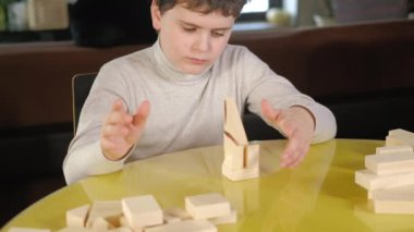 Masa oyunu. Anaokulundan bir çocuk oturma odasındaki masada küplerle oynuyor..