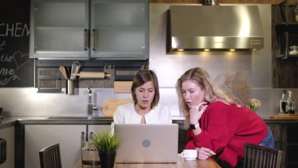 2人の白人の少女が遠隔地で働いている ビジネスの女性は台所の家のテーブルのコンピュータの仕事プロジェクトを論議する アイデアやブレインストーミングの交換 ビジネス上の議論と意思決定 — ストック動画