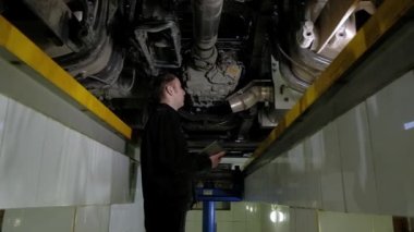 Üniformalı araba tamircisi benzin istasyonunda kamyon teftişi yapıyor. Müfettiş modern tabletteki tüm arızaları ve araba problemlerini kaydediyor. Mühendis garajda araba kaldırma makinesinin altında çalışıyor..