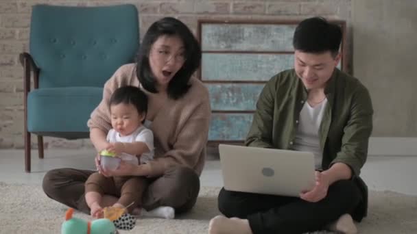 母亲和父亲照顾他们的孩子 亚洲家庭的父母和他们一岁的小儿子坐在一个舒适的房间的地板上 一个女人用瓶子喂她可爱的儿子奶 喂养婴儿 — 图库视频影像