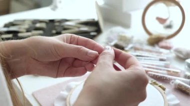 Genç tasarımcı kadın kumaşında güzel mücevherler ve nakış desenleri yaratıyor. İğne işi bir hobidir. Kadın ellerine yakın çekim. El nakışı için iğne ipliği.