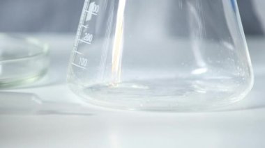 Yakın çekim büyük cam bir tüpe temiz bir solüsyon döker. Laboratuvar araştırması. İlaç kullanımı için farmakoloji endüstrisinde araştırma. Bir salgın sırasında ilaçların klinik denemeleri