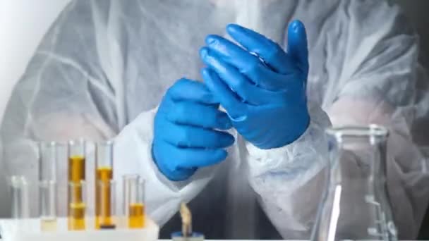 在临床医院的实验室里 身穿白色背景防护服的医学研究人员戴上防护手套 在实验室里进行实验 以找到防止病毒的疫苗 实验室研究 — 图库视频影像