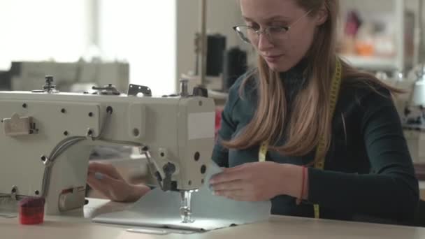 女时装设计师裁缝在服装厂的生产车间工作 工作室里的女孩根据准备好的草图和模板在专业缝纫机上缝制衣服 — 图库视频影像