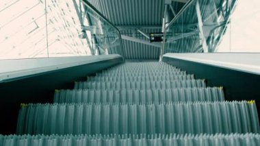 Boş yürüyen merdiven, iş merkezinde yükseliyor. İş merkezinde cam duvarları ve metal basamakları olan modern bir iç mekan. Metro 'da ulaşım merdiveni