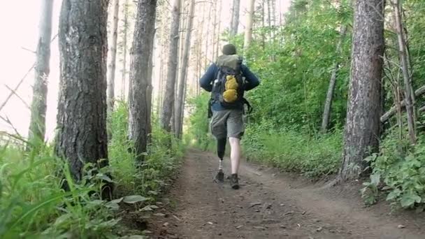 Ein Gehbehinderter Mann Mit Prothese Und Rucksack Geht Durch Den — Stockvideo