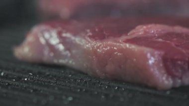 Mutfakta yemek pişirmek. Aşçı lezzetli bir akşam yemeği pişirmek için taze dana eti ya da et parçalarını sıcak ızgara tavaya koyar. Restoranın mutfağındaki ızgarada taze biftek pişiriliyor.