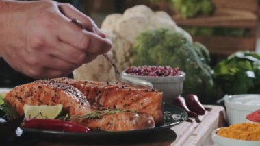 Şef, lezzetli bir somon bifteği ve beyaz krema sosu koyuyor. Yemeklere lezzet katmak için. Modern bir mutfakta hazırlanmış balık ve sebzeli leziz diyet öğle yemeği.