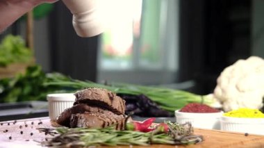 Mutfakta ızgara biftekler ve baharatlarla dolu. Pişirilmiş et parçaları biber kabından kokulu öğütülmüş biber ile pişirildi. Et pişirmek. Mutfakta barbekü.