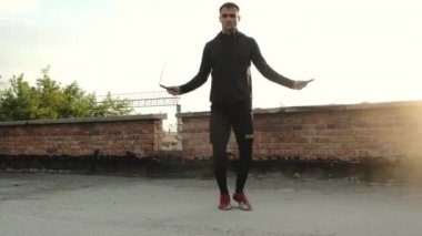 Açık havada halat eğitimi almış atlayan bir sporcu. Adam ip atlıyor. Çatıda kardiyo eğitimi. Spor acemisi temel atlama ipi alıştırması yapıyor.