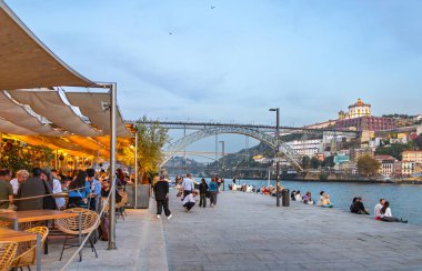 Nehrin arka planındaki tarihi merkezde kafe ve dolgu malzemesi ve Dom Luis Köprüsü, Portekiz, Porto, 17 Ekim 2025