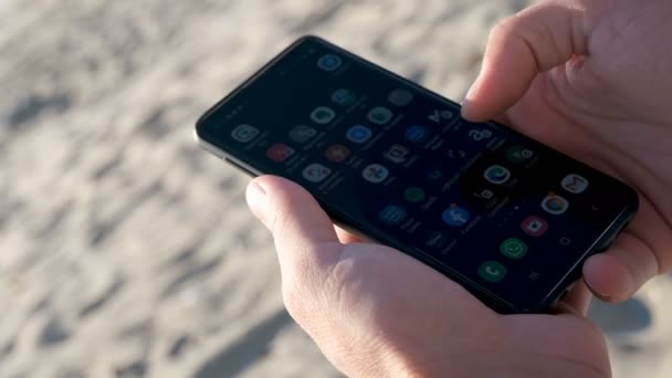 Cara usando smartphone para mídias sociais e bate-papo no pôr do sol luz do mar, celular — Vídeo de Stock