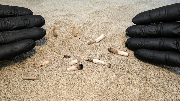 Man collecting used cigarette butts discarded on sandy sea beach,ecosystem habitat pollution — Stock Photo, Image