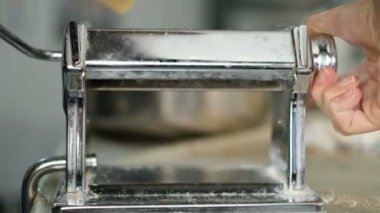 Woman while peparing food with dough sheeter in kitchen,homamade pastry,lockdown
