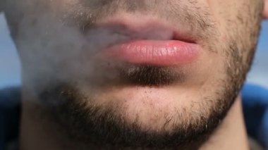 Genç sakallı adam sigara üflerken yakın görüş, tütün bağımlılığı, sağlıksız yaşam tarzı