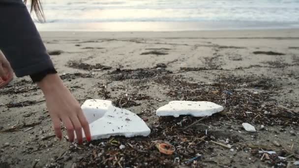Young woman pick up polystyrene plastic from dirty ocean coast after sea storm,environmental protection concept — Stock Video