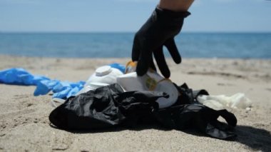 İnsan deniz kenarında koruyucu maske ve plastik eldiven toplar, koronavirüs kirliliği