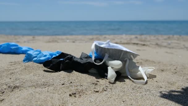 Omvallen masker en plastic handschoenen op zeekust, coronavirus vervuiling slow motion — Stockvideo