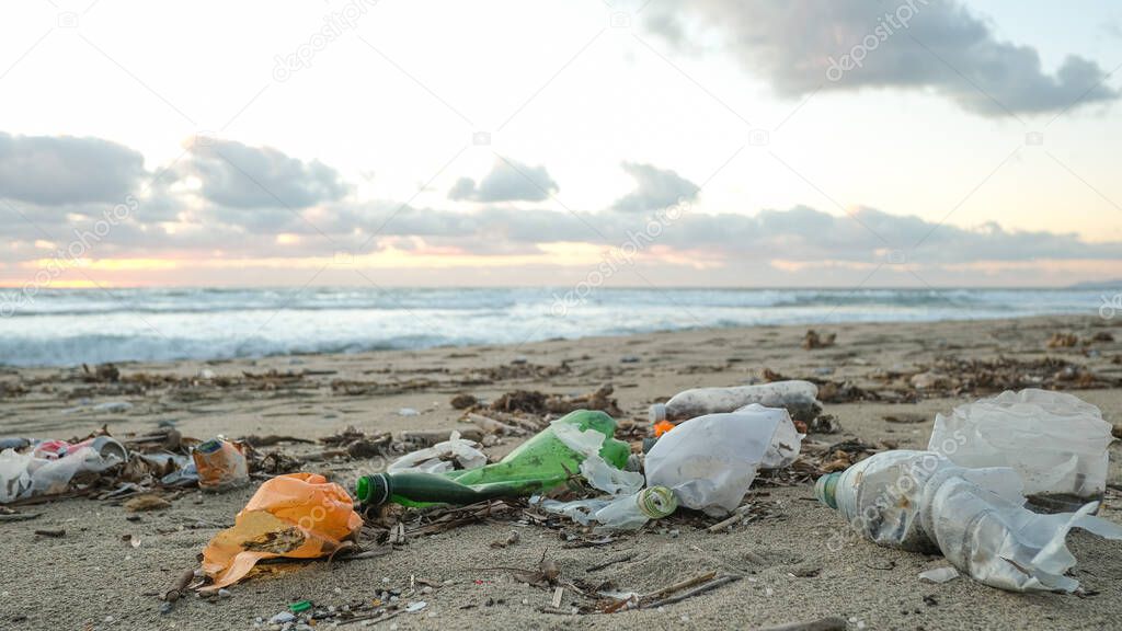 Plastic bottles trash pollution on contaminated ocean sea coast,sunset time,environmental waste