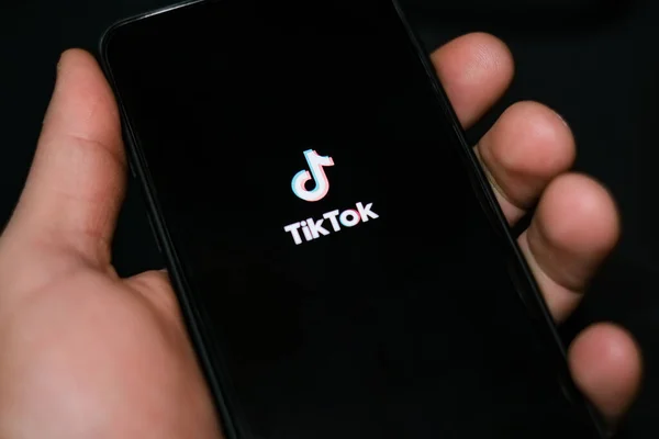 Genç adam tiktok uygulaması, sosyal ağ teknolojisi bağımlılığı kullanırken akıllı telefonu tutuyor.