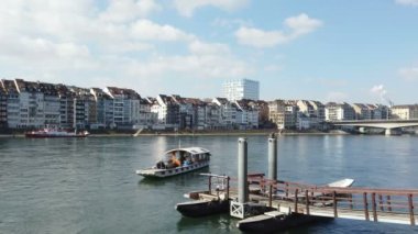 Basel şehri nehir kenarının geniş açılı manzarası turist botu ve ünlü köprüsü, İsviçre simgeleri.