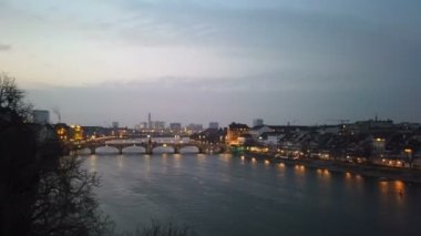 Aydınlatılmış Basel şehri nehir kenarındaki gökyüzü, günbatımı gecesi, İsviçre simgeleri