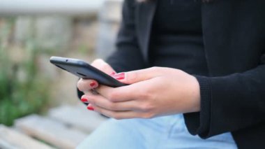 Genç kadın parkta akıllı telefon kullanıyor, sosyal ağ teknolojisi bağımlısı.