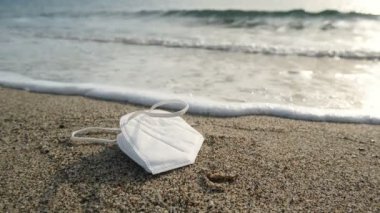 Kirli deniz kıyısında yüzen tek kullanımlık yüz maskesi, kovid19 salgın hastalık