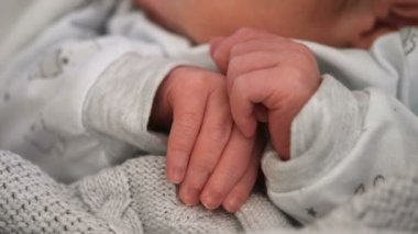 Küçük sevimli yeni doğmuş çocuk uyurken ellerini kapar, masum aile sevgisi kavramı.