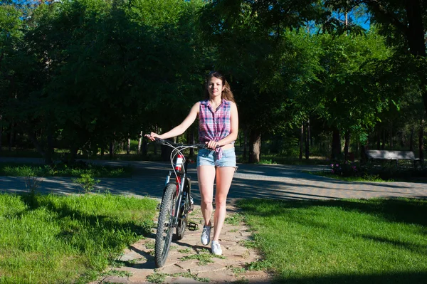 Chica sonriente caminando con su bicicleta — Foto de Stock