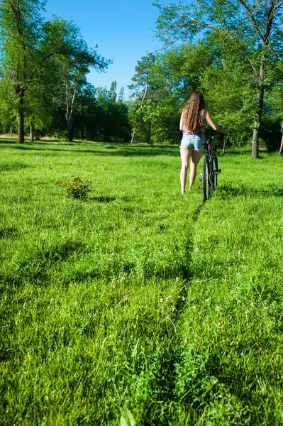 Chica saliente con su bicicleta — Foto de Stock