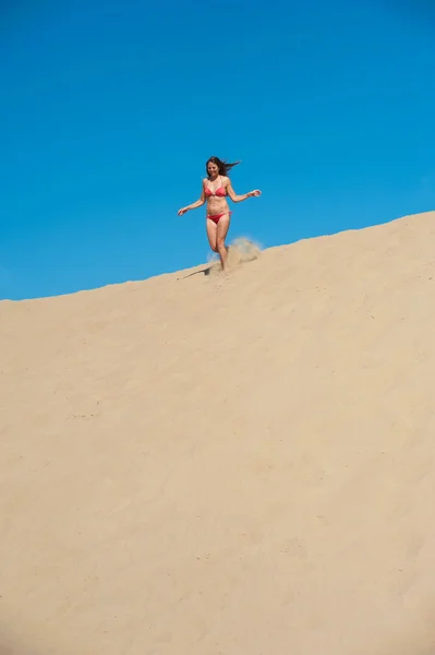 Menina de biquíni vermelho correndo na areia — Fotografia de Stock