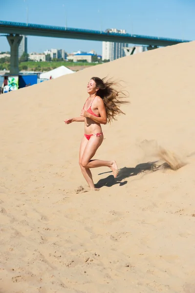 Menina de biquíni vermelho correndo na areia — Fotografia de Stock