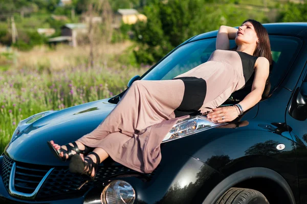 Pretty woman lying on the car. — Stock Photo, Image