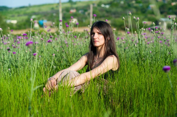 Mladá žena, sedící v trávě — Stock fotografie