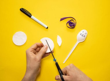 Sarı arka planda plastik kaşık ve pamuktan Paskalya tavşanı yapmak. Ev yapımı çocuk oyuncağı. Basit yaratıcı sanat projesi. Adım adım. Bahar için dekorasyon. Diy konsepti. Adım 3