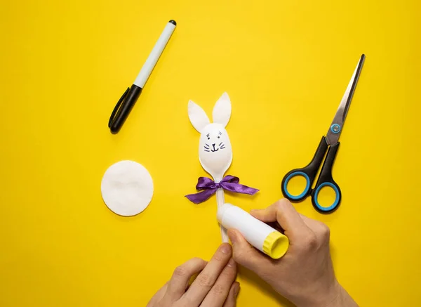 Sarı arka planda plastik kaşık ve pamuktan Paskalya tavşanı yapmak. Ev yapımı çocuk oyuncağı. Basit yaratıcı sanat projesi. Adım adım. Bahar için dekorasyon. Diy konsepti. 7. Adım