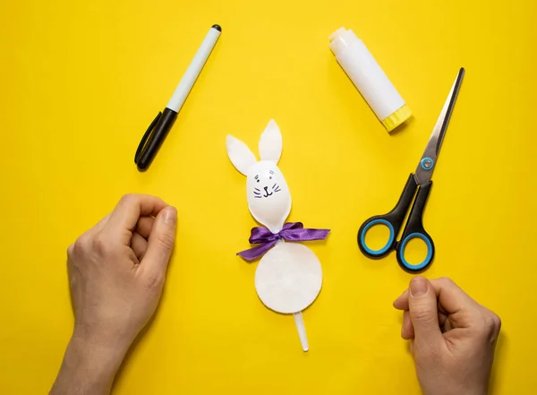 Sarı arka planda plastik kaşık ve pamuktan Paskalya tavşanı yapmak. Ev yapımı çocuk oyuncağı. Basit yaratıcı sanat projesi. Adım adım. Bahar için dekorasyon. Diy konsepti. 8. Adım