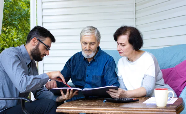 Senior couple planning retirement with finance consultant, sitting at home terrace. Realtor consulting mature family about buying home, taking mortgage loan, making investment or real estate deal — Stock Photo, Image