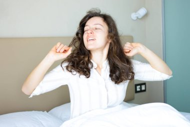 Yatakta uzanan mutlu esmer kadın otelde tek başına uyanıyor. Sağlıklı bir uykudan uyanır, rahat bir yatak odasında oturur, günaydın, yeni günün tadını çıkarır. Kavramı uyandırma zamanı.