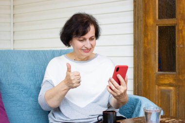 Akıllı telefon kullanmaktan mutlu bir son sınıf öğrencisi. Video araması yapıyor. Başparmağının işaret gibi onayını veriyor. İnternetten torunlarını arıyor. Kablosuz internet kullanıyor, terasta oturuyor.