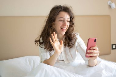 Güzel esmer kız akıllı telefon ekranına bakıp gülümsüyor, kapalı bir odada oturuyor. Kablosuz internet bağlantısı, mesaj yazma, online alışveriş, rezervasyon, e-posta kontrolü, sosyal medya